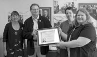 Connie St. George, Wolfgang Miska and Dorothea Langevin accept the August 2006 Business of the Month plaque from Beth Crosby of the Chamber.