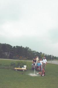 The picture shows Gary Lussier-Thompson at the launcher, Kenny Dalley (in wheelchair) doing the countdown, Casey Dalley in another wheelchair, teaching assistant Helyn Anderson in white, Suzanne Sampson in black, Derek Larson, and teaching assistant Jeremy Ackton (in back so his stomach bulge wouldn’t show). 