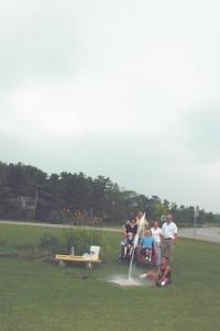 The picture shows Gary Lussier-Thompson at the launcher, Kenny Dalley (in wheelchair) doing the countdown, Casey Dalley in another wheelchair, teaching assistant Helyn Anderson in white, Suzanne Sampson in black, Derek Larson, and teaching assistant Jeremy Ackton (in back so his stomach bulge wouldn’t show).
