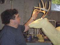 Butch looks over a set of horns and a deer head foam in his workshop and taxidermy studio in Middlebury.