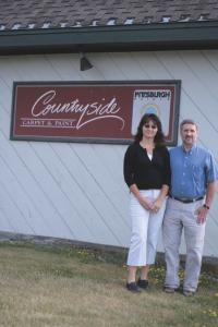 Janice & Eric Denu in front of the existing Countryside Carpet & Paint building.