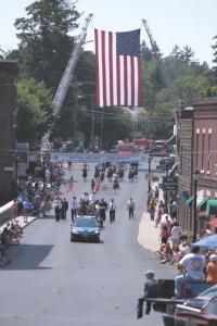 Ladder trucks support a large American Flag forming an arch for fire departments from all over Vermont to be recognized during this years state convention hosted by The Addison County Firefighters Association.