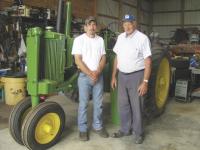 Al and his grandson Joe stand together by a John Deere
A tractor that is currently in their shop under restoration.