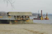 Materials for a new dock are stockpiled at Chimney Point. Visible on the lake behind is a barge with an engineering crew making test borings to determine where and how to build the dock. 