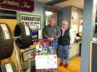 Steve & Lisa Dupoise of County Tire Center stand by one of the shopping carts they are seeing fill up during their 5th Annual Food Drive & Break Inspection program benefiting HOPE of Addison County.